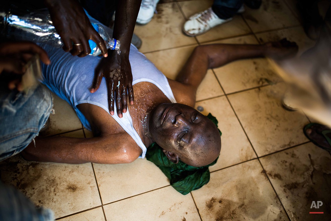  Protestors  pour  water on a  injured man near the parliament building in Burkina Faso as people protest  against their longtime president Blaise Compaore who is seeking another term in Ouagadougou, Burkina Faso, Thursday, Oct. 30, 2014. Protesters 