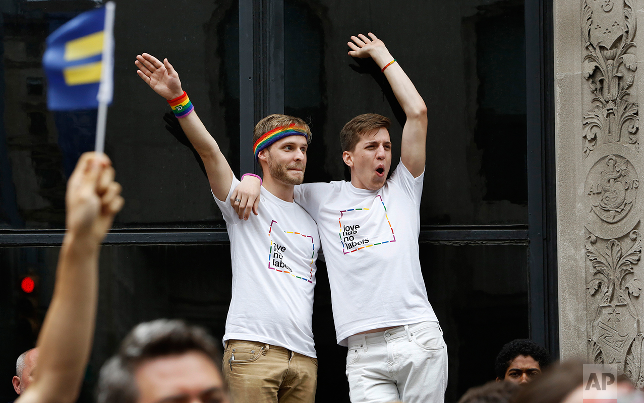  A couple watch from a perch above the crowd as floats blaring loud and rhythmic music pass by during the Heritage Pride March in New York,&nbsp;June 28, 2015.&nbsp;(AP Photo/Kathy Willens) 