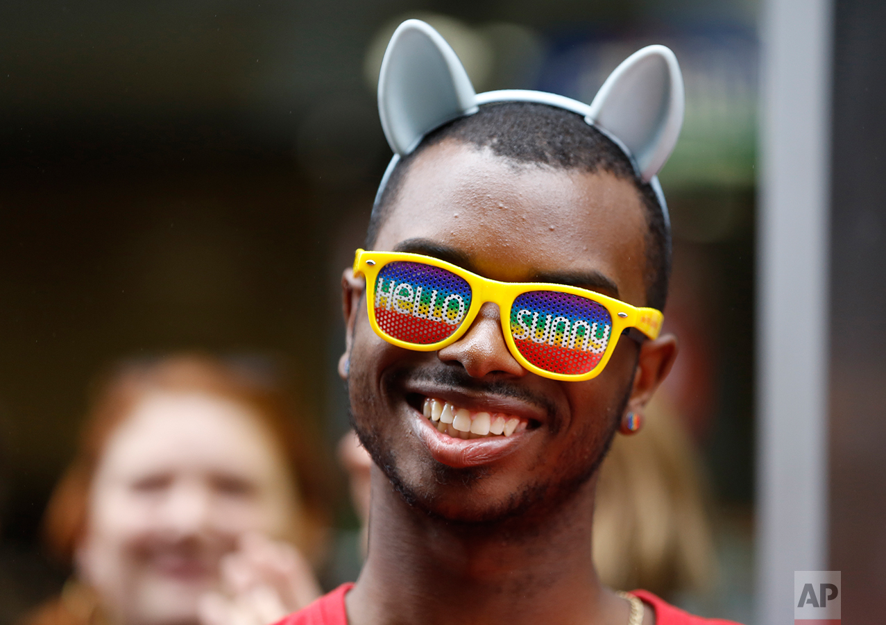  Julian Sims, of Meriden, Conn., wears "Hello Sunny" glasses and rainbow-colored earrings as he watches floats and people parade down New York's Fifth Avenue during the Heritage Pride March in New York,&nbsp;June 28, 2015. (AP Photo/Kathy Willens) 