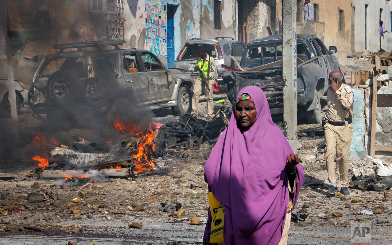 A woman walks past the scene of a suicide car bomb attack on a police station in Mogadishu, Somalia Thursday, June 22, 2017. A number of people are dead and several others wounded in the blast in Somalia's capital, police said Thursday, adding that the bomber was trying to drive into the police station's gate but detonated against a wall. (AP Photo/Farah Abdi Warsameh)