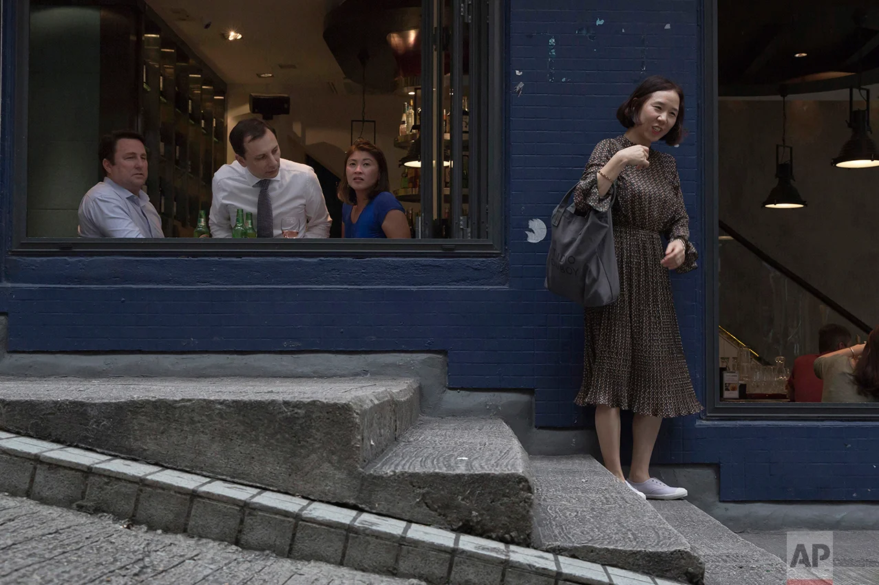 In this May 25, 2017, photo, a man inside a bar looks towards a woman in Central district, Hong Kong. (AP Photo/Kin Cheung)