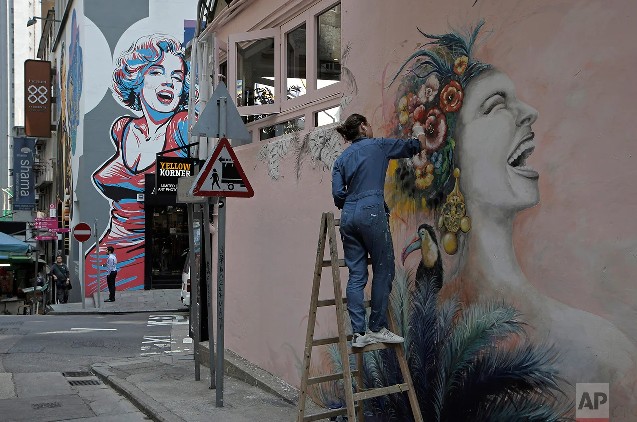 In this March 2, 2017 photo, a woman draws on wall in Central district, Hong Kong. (AP Photo/Kin Cheung)