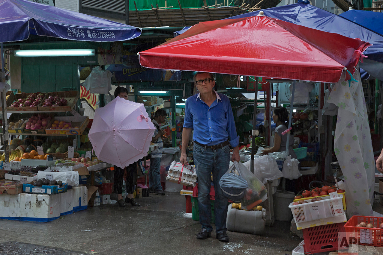 In this June 12, 2017, photo, a man takes shelter from a storm at a local market on the slope in Central district, Hong Kong. (AP Photo/Kin Cheung)