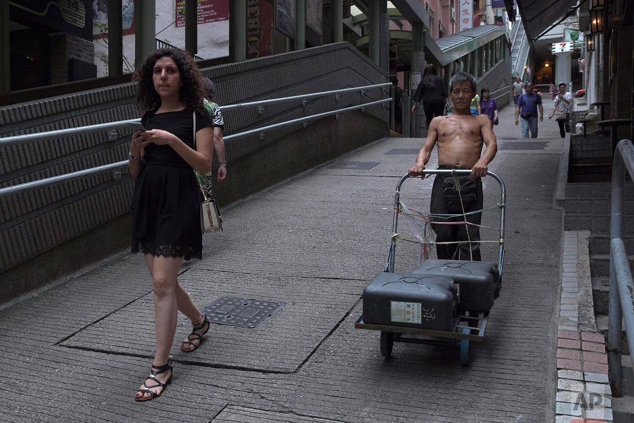 In this May 20, 2017, photo, a man pushes a trolley down the slope in Central district, Hong Kong. (AP Photo/Kin Cheung)