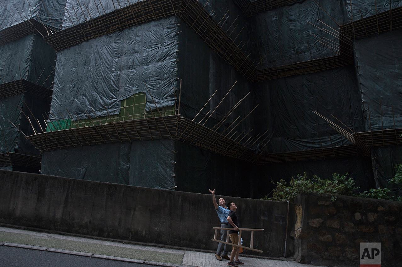 In this May 20, 2017, photo, two workers walk down the slope near a construction site in Central district, Hong Kong. (AP Photo/Kin Cheung)