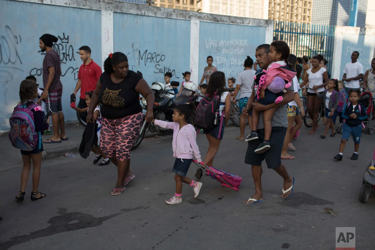 In this June 7, 2017 photo, Bruna Pedro, left, walks her daughter Kamylle to her school's entrance in the City of God slum of Rio de Janeiro, Brazil. (AP Photo/Leo Correa)