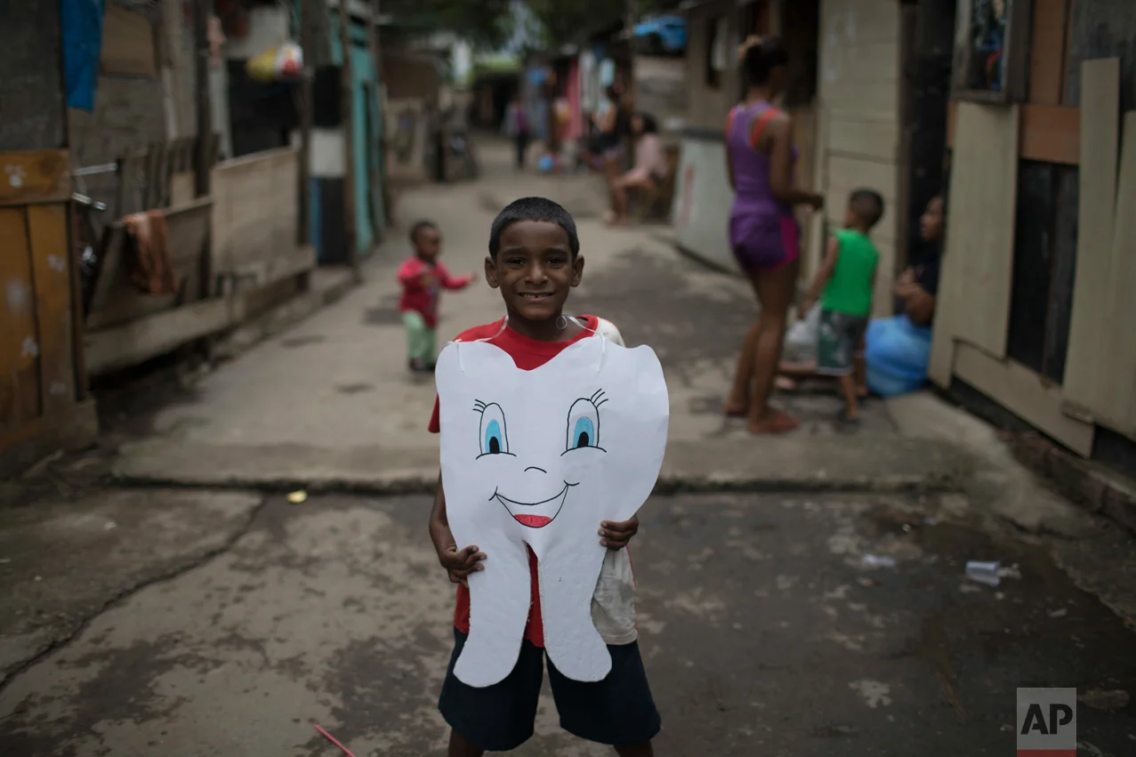 In this June 10, 2017 photo, a youth poses for the picture wearing a healthy tooth costume given to him by an NGO in one of the poorest area of the City of God slum in Rio de Janeiro, Brazil. (AP Photo/Leo Correa)