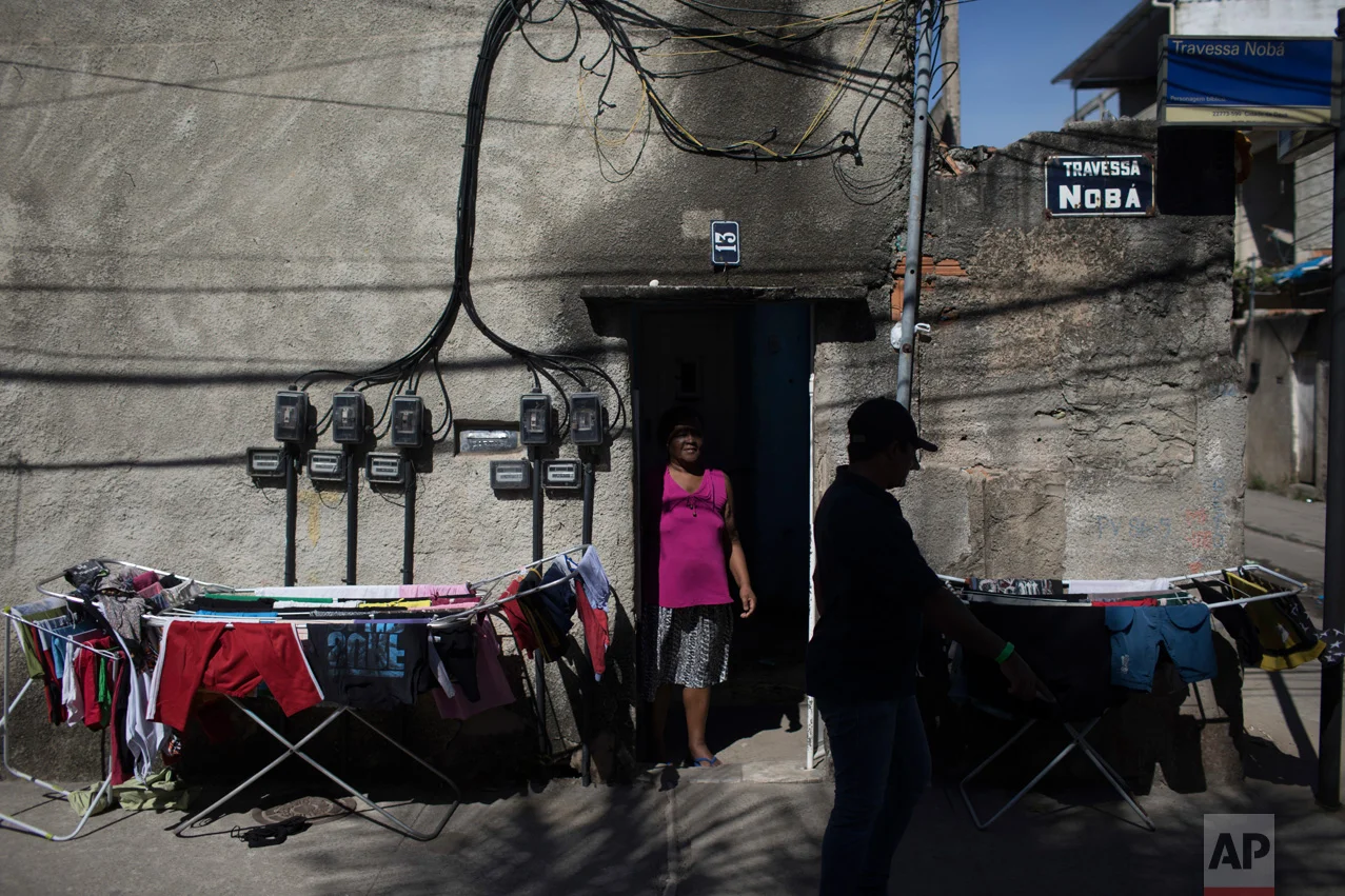 In this June 8, 2017 photo, evangelical pastor Silvio Cesar Soares Gonzaga is silhouetted as he walks past the home of Celina, an elderly woman who helped him after he left a life of drug trafficking in the City of God slum of Rio de Janeiro, Brazil. (AP Photo/Leo Correa)