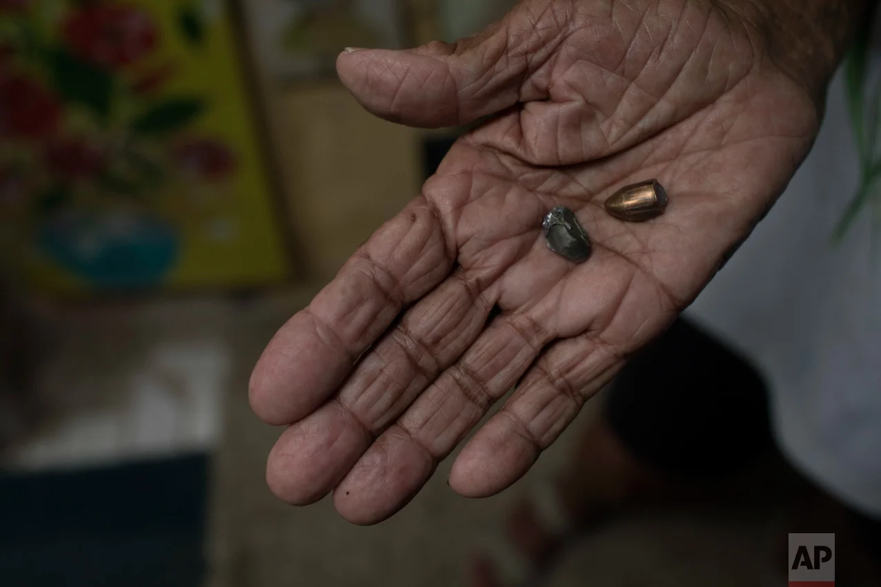 In this June 8, 2017 photo, artist Anayde dos Santos Muniz holds two bullets that recently hit her home near her bed in the City of God slum of Rio de Janeiro, Brazil. (AP Photo/Leo Correa)
