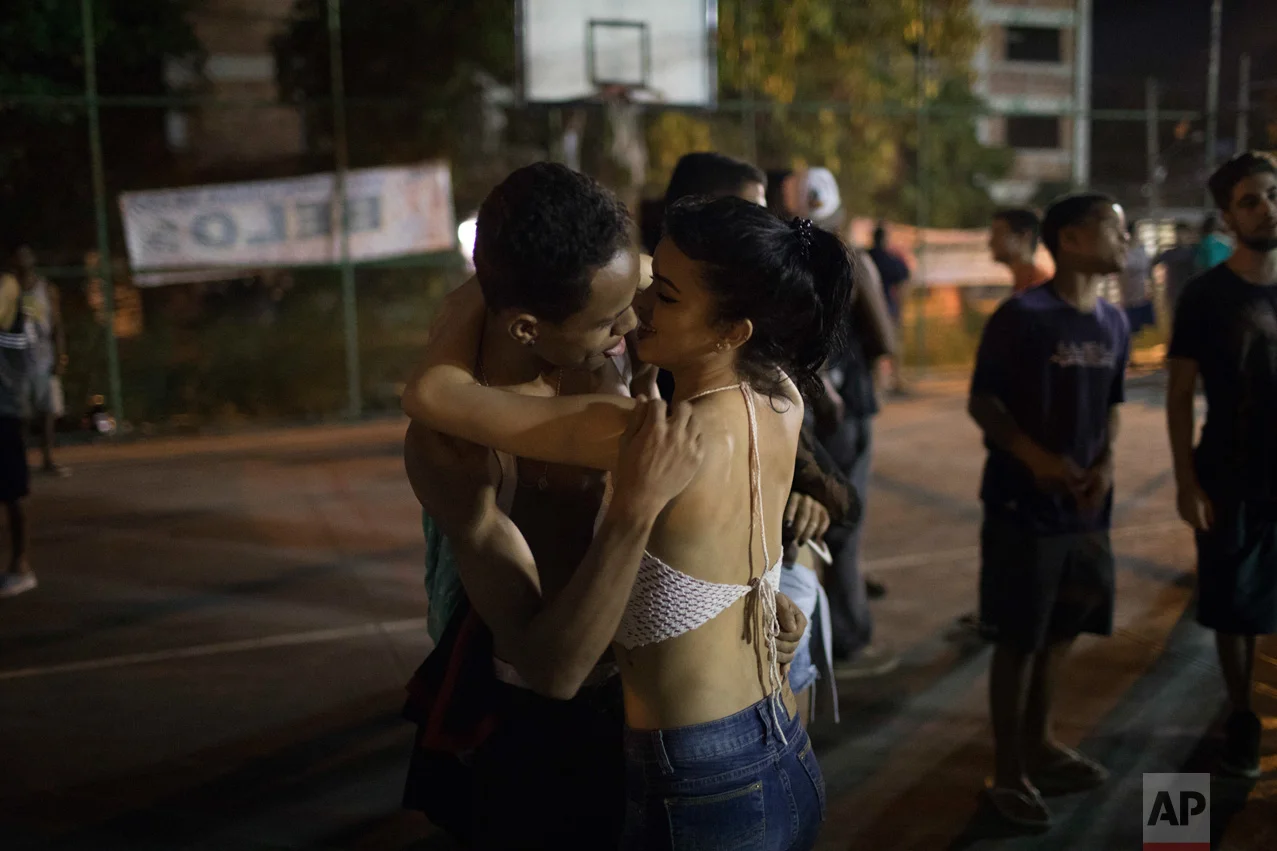In this June 8, 2017 photo, a couple kiss on the sidelines of a night rap battle session in the City of God slum of Rio de Janeiro, Brazil. (AP Photo/Leo Correa)