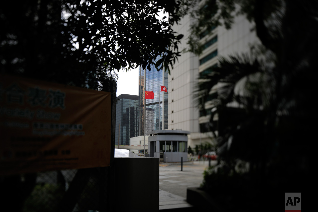 In this June 12, 2017, photo made with a tilt-shift lens, a Chinese national flag and a Hong Kong flag are flown at the High Court in Hong Kong. Under the "one country, two systems" principle, Hong Kong retains an independent judiciary, setting it apart from mainland China. Two decades since Beijing took control of Hong Kong, China's rising influence – and Britain's waning profile – are impossible to ignore. (AP Photo/Vincent Yu)