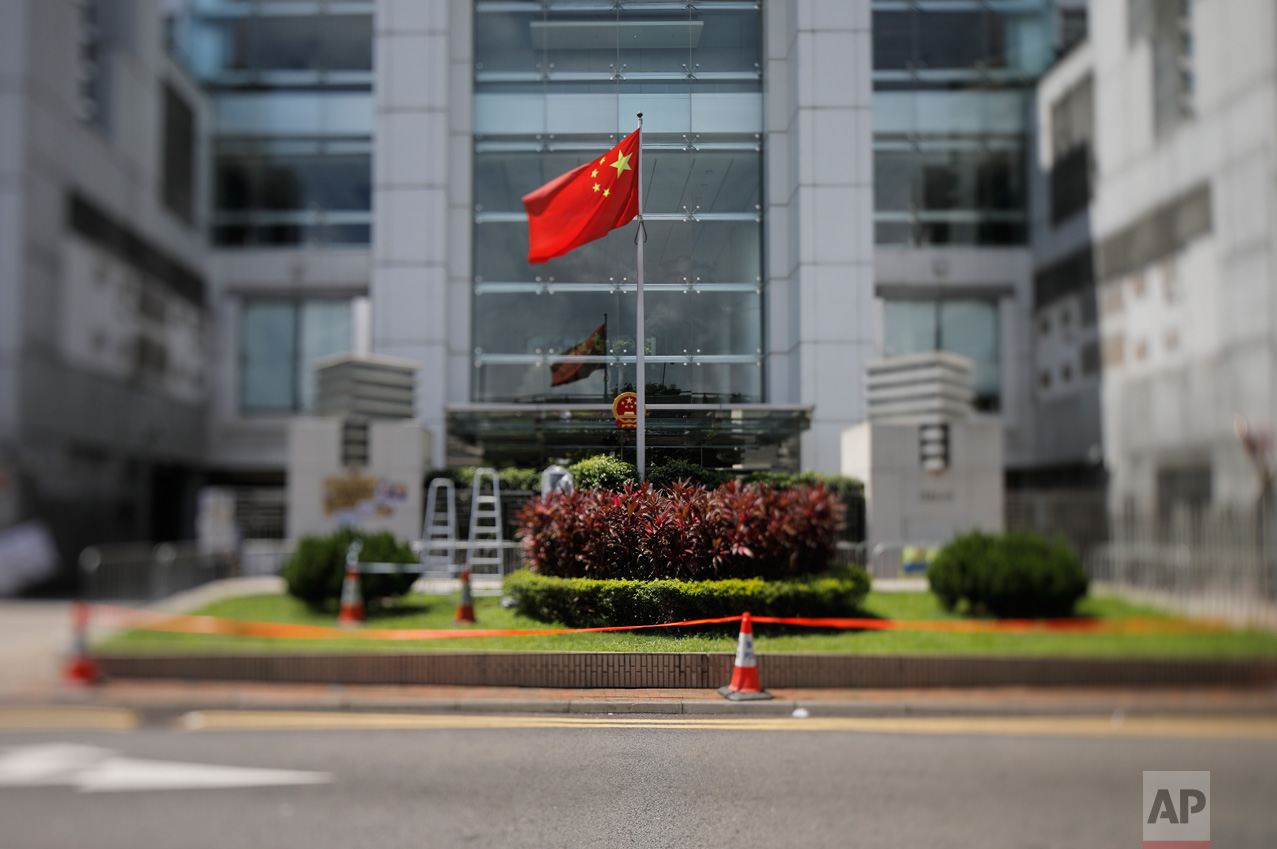 In this June 27, 2017, photo made with a tilt-shift lens, a Chinese national flag is flown at the the Chinese central government's Liaison Office in Hong Kong. The office is a frequent target of protests by pro-democracy supporters, who believe that officials stationed there are the real power in Hong Kong. Two decades since Beijing took control of Hong Kong, China's rising influence – and Britain's waning profile – are impossible to ignore. (AP Photo/Vincent Yu)