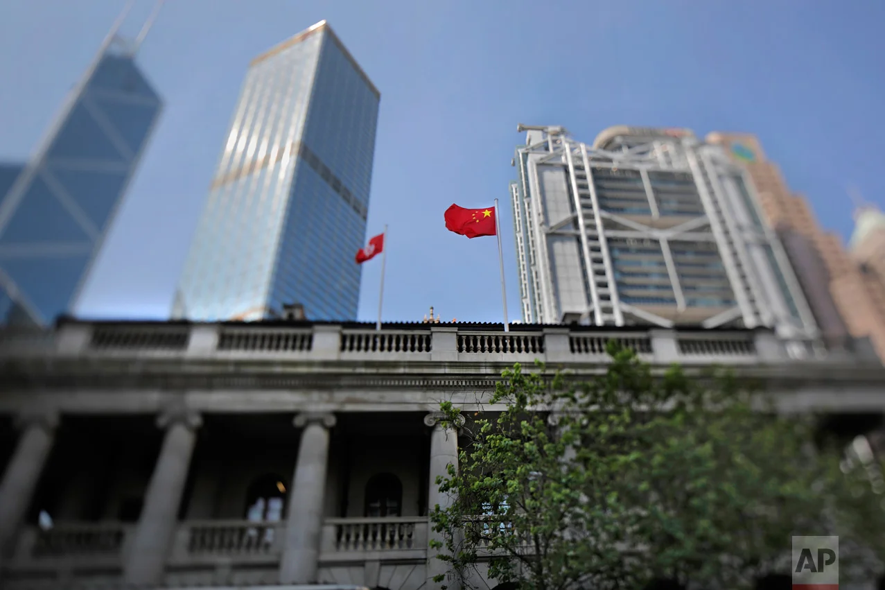 In this May 29, 2017, photo made with a tilt-shift lens, a Chinese national flag and a Hong Kong flag fly above the Court of Final Appeal in Hong Kong. (AP Photo/Vincent Yu)
