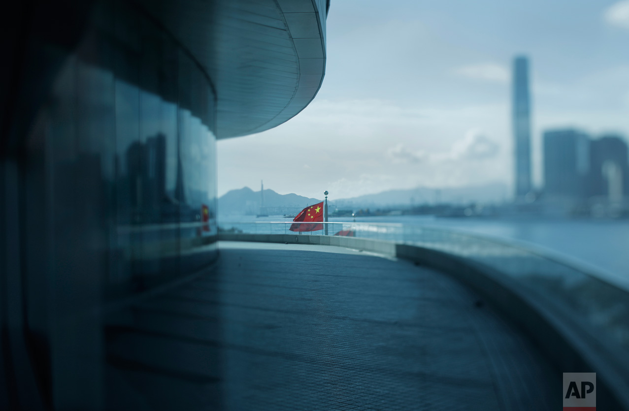 In this June 7, 2017, photo made with a tilt-shift lens, a Chinese national flag flies at the Convention and Exhibition Center in Hong Kong. Hong Kong's massive waterfront convention center was the venue for 1997's handover ceremonies, where Chinese and Beijing officials presided over the transfer of power beginning at midnight on June 30, 1997. It will be a key location for the 20th anniversary events attended by President Xi Jingping. (AP Photo/Vincent Yu)