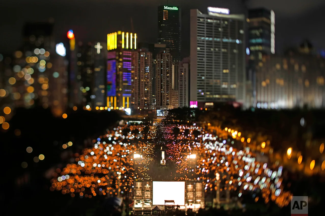 In this June 4, 2017, photo made with a tilt-shift lens, tens of thousands of people attend a candlelight vigil in Victoria Park in Hong Kong for victims of the Chinese government's military crackdown nearly three decades ago on protesters in Beijing's Tiananmen Square. Two decades since Beijing took control of Hong Kong, China's rising influence – and Britain's waning profile – are impossible to ignore. (AP Photo/Vincent Yu)