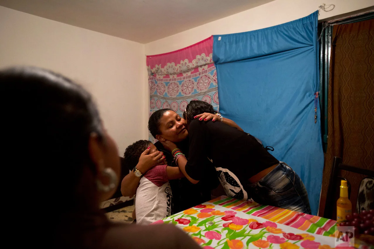 In this June 27, 2017 photo, Honduran refugee Laura Maria Cruz Martinez is hugged by her children Ruth, 12, right, and Josue, 7, after Ruth serenaded her with a song that thanks a single mother for the struggle and strength with which she raised her children, drawing tears from Laura, in the two-bedroom apartment they share with another refugee family in Mexico City. (AP Photo/Rebecca Blackwell)