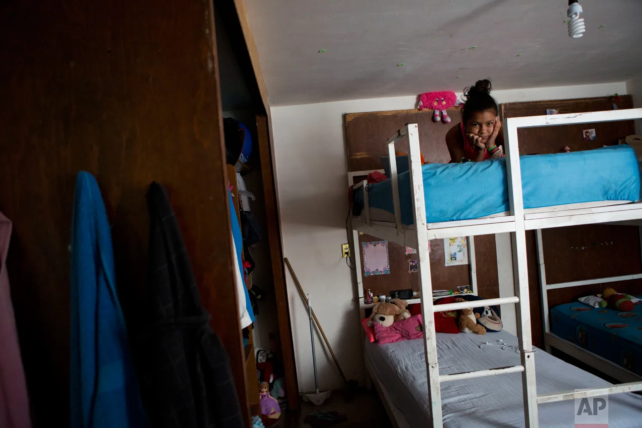 In this June 22, 2017 photo, Ruth Funez Cruz, 12, from Honduras, rests on her bunkbed in the room she shares with her mother, her cousin, and two siblings, in their apartment in the Iztapalapa district of Mexico City. (AP Photo/Rebecca Blackwell)