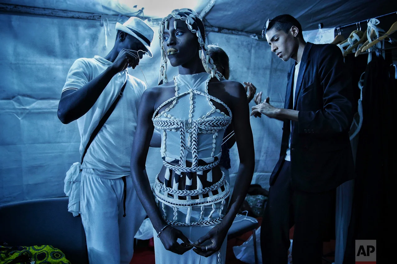 Designer Oumar Dicko, right, of Mali and Belgium, laces up a model in one of his creations backstage during Dakar Fashion Week in the Senegalese capital, Saturday July 1, 2017. (AP Photo/Finbarr O'Reilly)