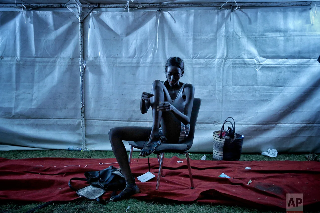 A models ties her sandals after the finale of Dakar Fashion Week in the Senegalese capital, Friday July 1, 2017. (AP Photo/Finbarr O'Reilly)