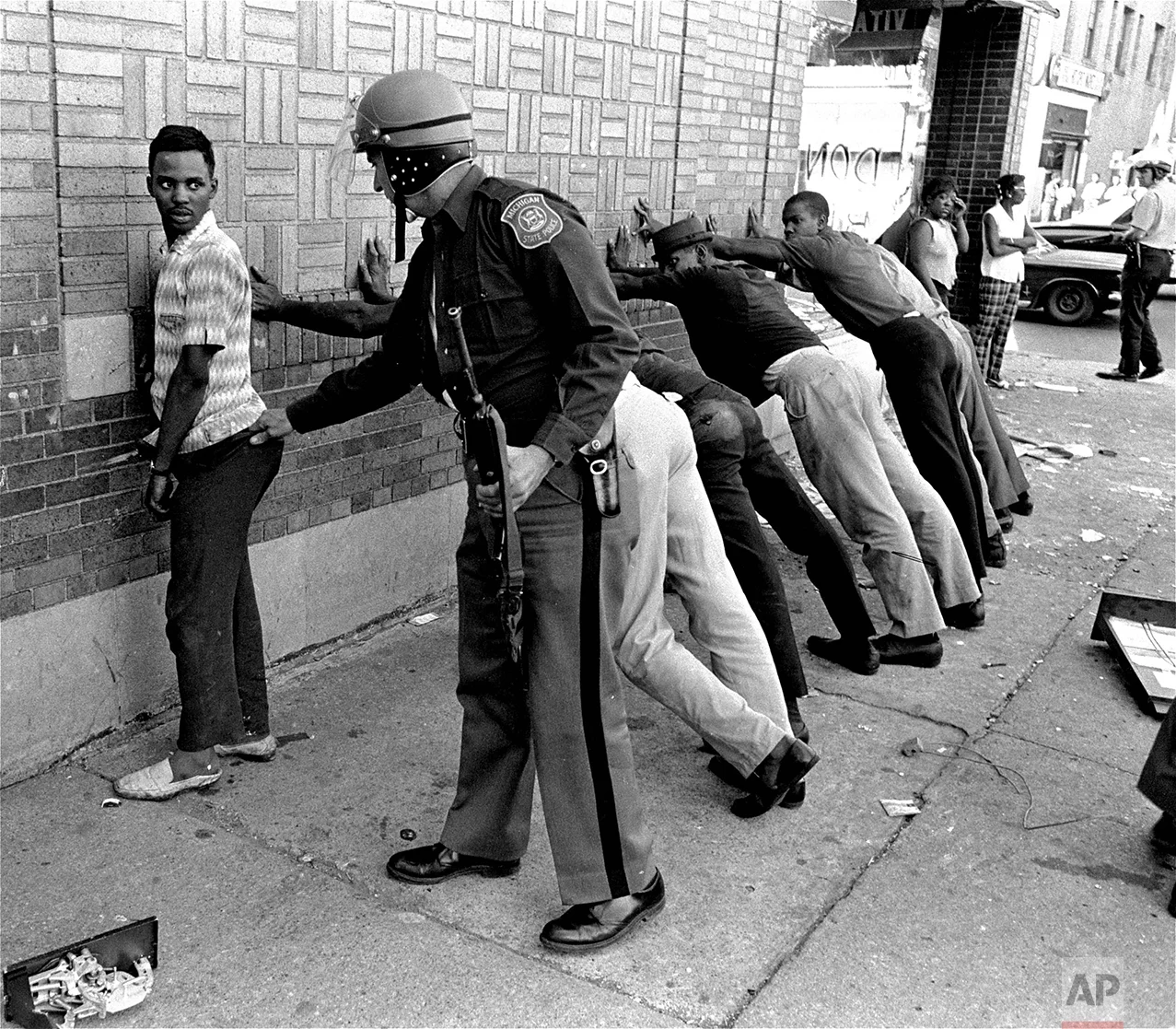 A Michigan State officer searches a youth on Detroit's 12th Street, July 24, 1967, where looting was still in progress after the city's rioting. His companions lean against the wall waiting their turn. There were many arrests and at least five persons were dead. (AP Photo)