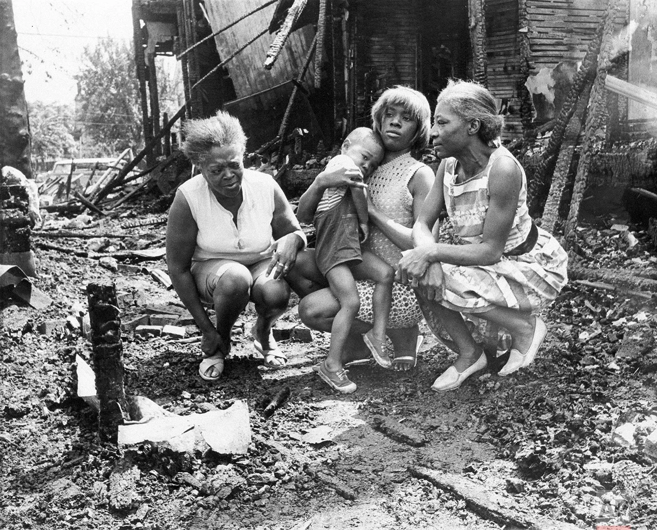 Three women and a child visit the charred ruins of what used to be their home in the 12th Steet area of Detroit, Mich., July 26, 1967. Homes were burned out by fire bombs thrown by rioters. The women are typical of many innocent people who lost all of their possessions in the fires. from Left are: Mrs. Willie Moore; Mrs. Elizabeth Allen, holding son, Thomas, 3; and Mrs. Louella Underwood. (AP Photo/Detroit News)