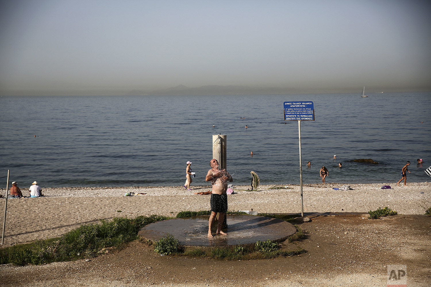 A man takes a shower at a beach of Alimos suburb in Athens, on Saturday, July 1, 2017. (AP Photo/Yorgos Karahalis)