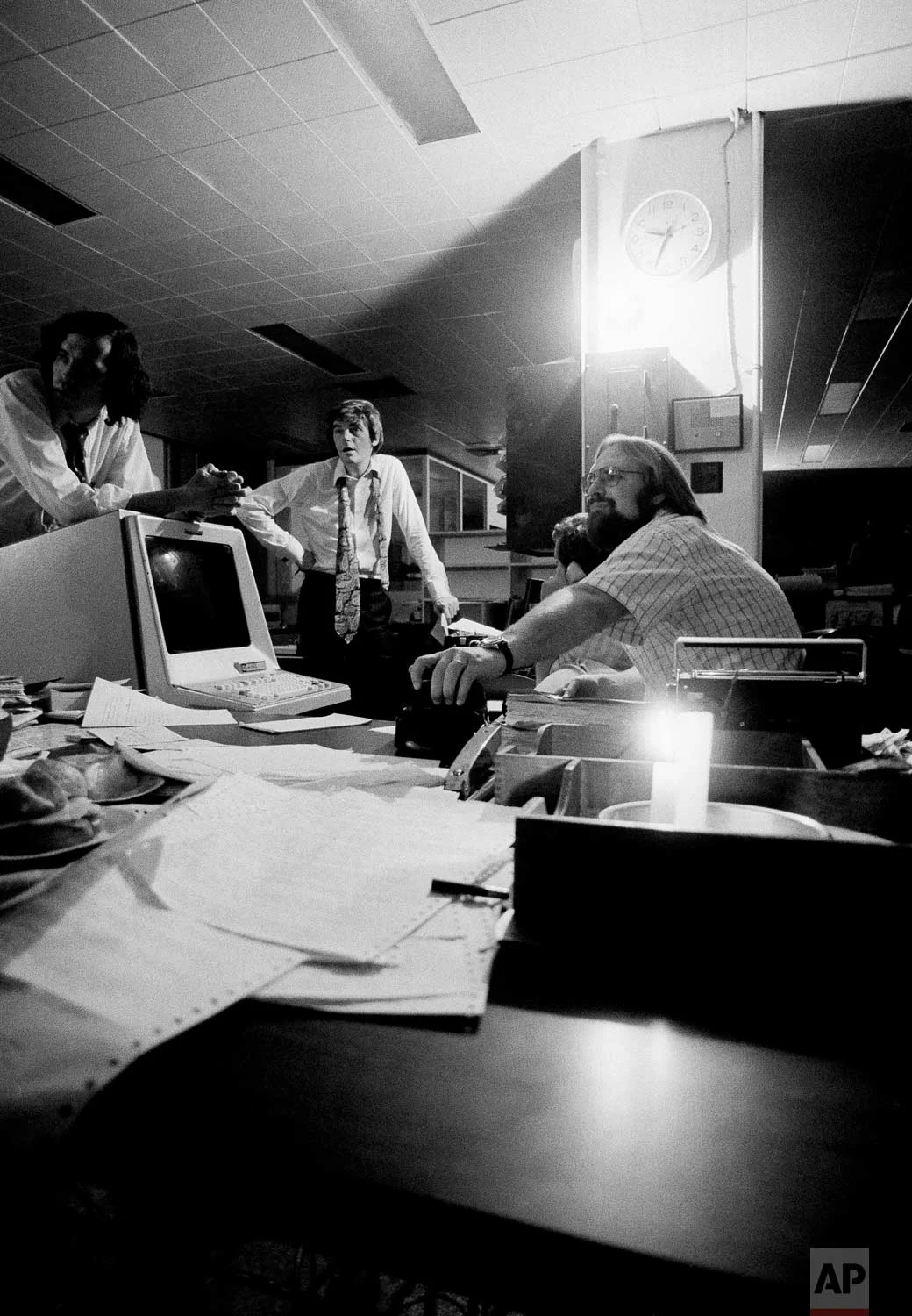 Using emergency power, staffers on the Associated Press general desk plan coverage of the blackout in New York City, July 13, 1977, in New York. Clock at upper right shows time power went out at AP. (AP Photo/Cameron Bloch)