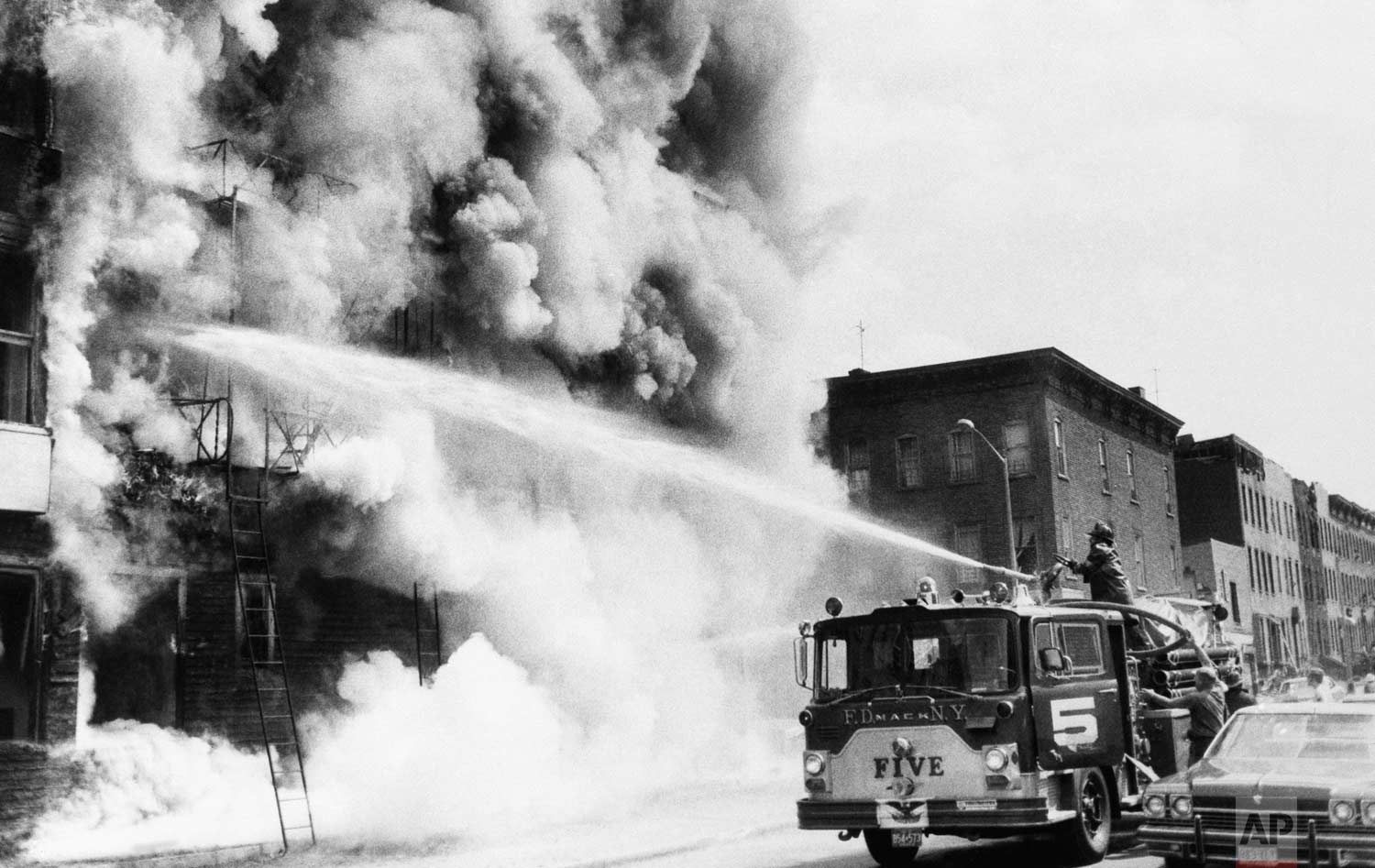  Firemen fight a blaze above a row of looted stores in New York's Brooklyn borough, July 14, 1977, the day after the power failure. The stores were looted during blackout. (AP Photo) 