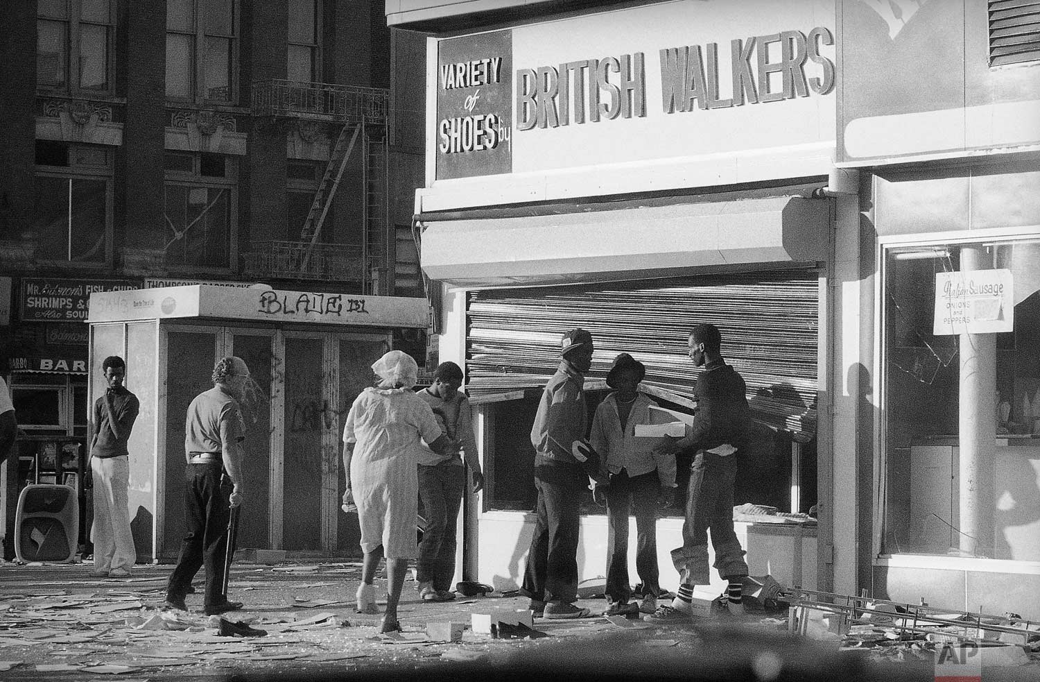  Looters in Manhattan's Harlem section reach past a bent security gate to ransack the window of a shoe store in New York on Thursday, July 14, 1977. A massive power failure in the metropolitan New York area on Wednesday led to acts of vandalism in so
