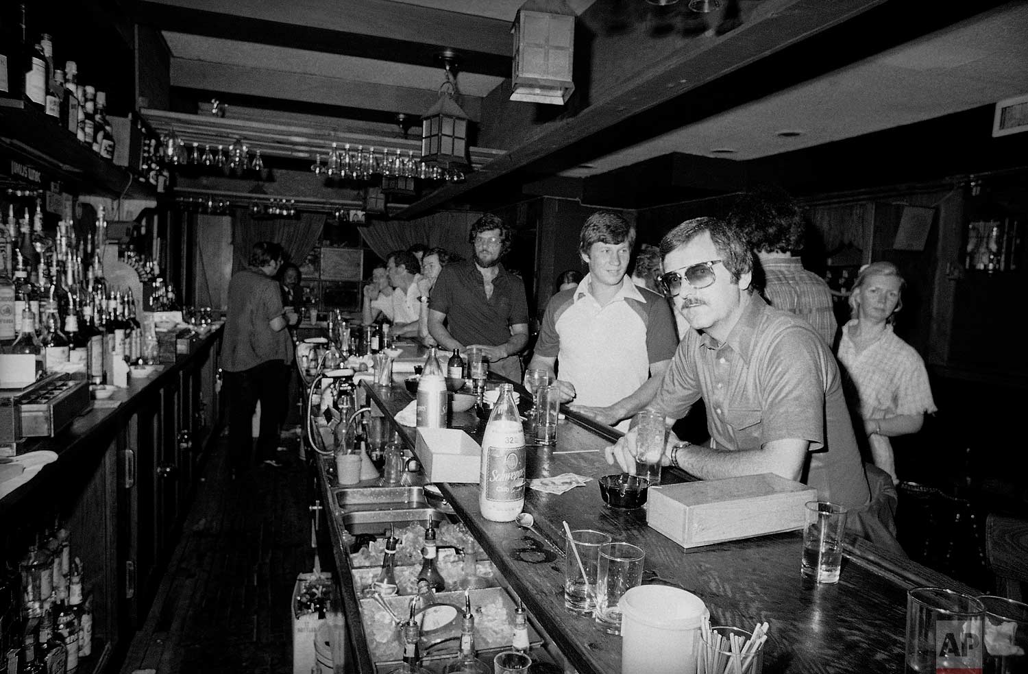  People in a midtown Manhattan bar keep drinking by candlelight in New York on Wednesday, July 13, 1977 after the city was struck by a power failure. (AP Photo/Steve Oualline) 