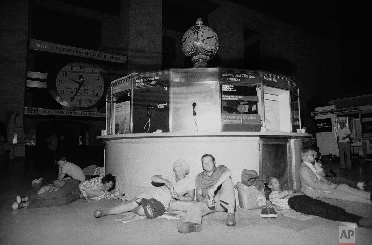  People huddle against the information kiosk in New York's Grand Central Station, Thursday, July 14, 1977 after being stranded by a power failure in the city, its boroughs and some neighboring areas. Grand Central is a crossroad for commuter trains a