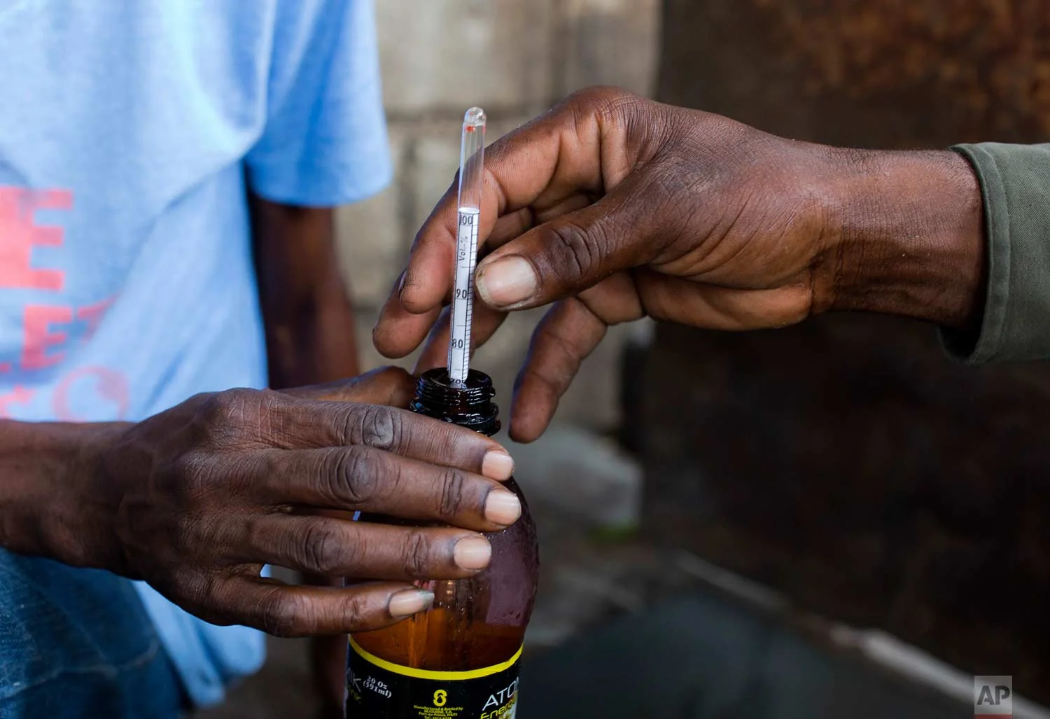 In this June 16, 2017 photo, workers measure the level of alcohol before watering down a sugar-based drink known as clairin to bring it to 45 or 50 percent alcohol content, at the Ti Jean distillery in Leogane, Haiti. Clairin, or kleren as it's known in Haitian Creole, is the rustic cousin of Haiti's most famous export: Barbancourt rum. (AP Photo/Dieu Nalio Chery)