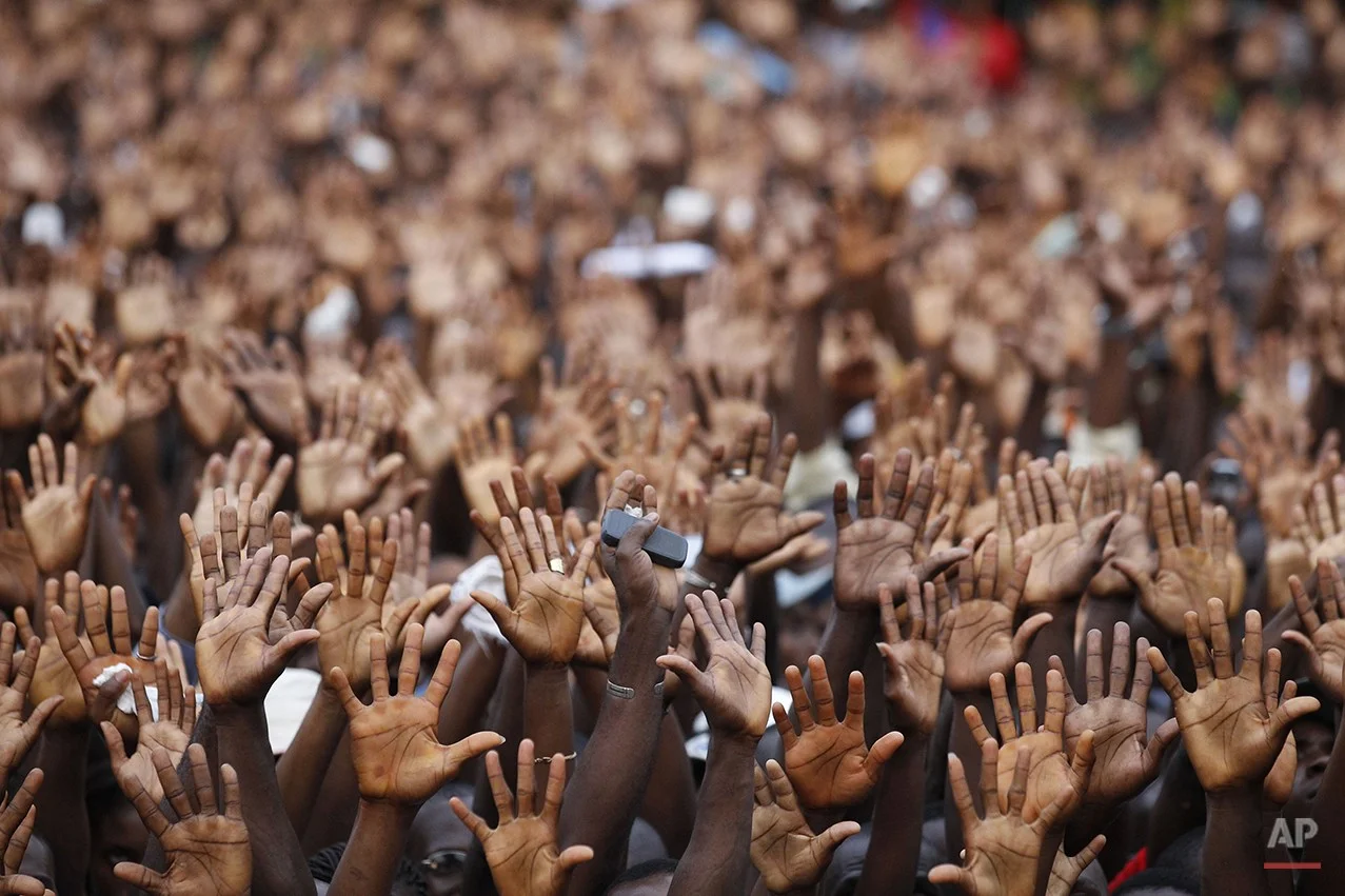  Supporters of incumbent president Laurent Gbagbo raise their hands in a show of support, at a pro-Gbagbo rally in the Yopougon district of Abidjan, Ivory Coast, Sunday, Jan. 9, 2011. Former Nigerian President Olusegun Obasanjo was shuttling between 