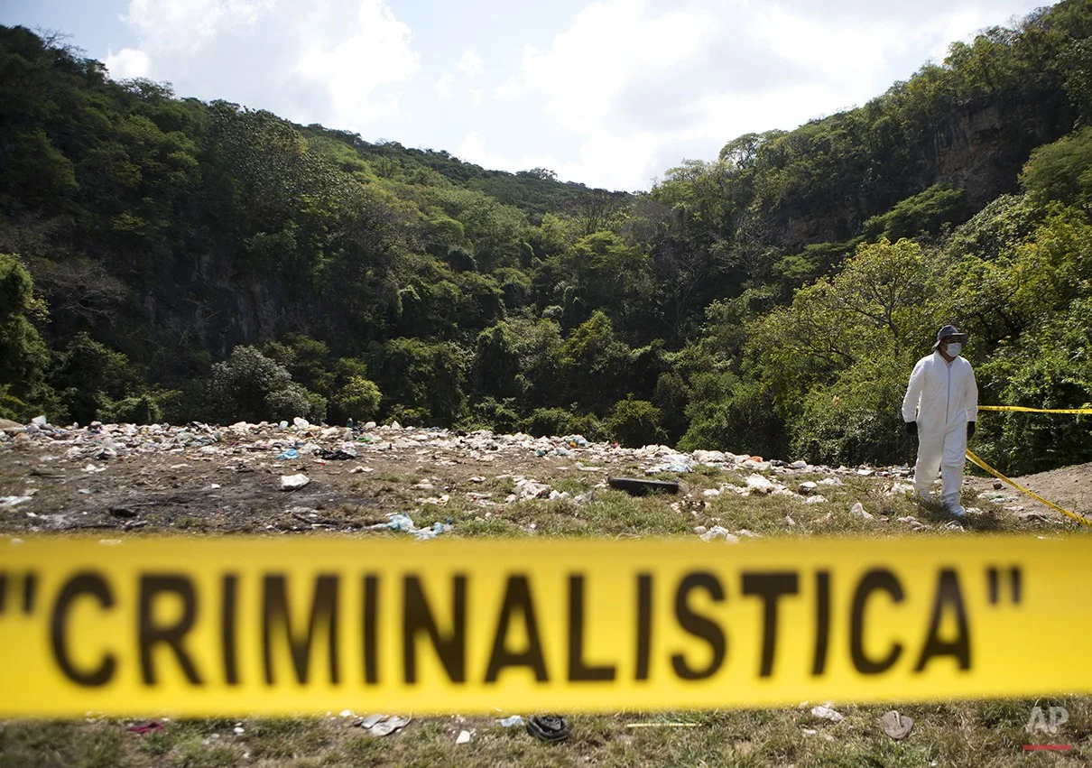  A forensic examiner walks along a garbage-strewn hillside above a ravine where examiners are searching for human remains in densely forested mountains outside Cocula, Guerrero state, Mexico, Tuesday, Oct. 28, 2014. Suspects arrested this week told p