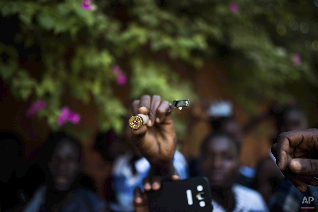  In this photo taken Thursday, Oct. 30, 2014, a protester hold up a bullet as they go on a rampage near the parliament building in Burkina Faso as people protest against their longtime President Blaise Compaore who seeks another term, in Ouagadougou,