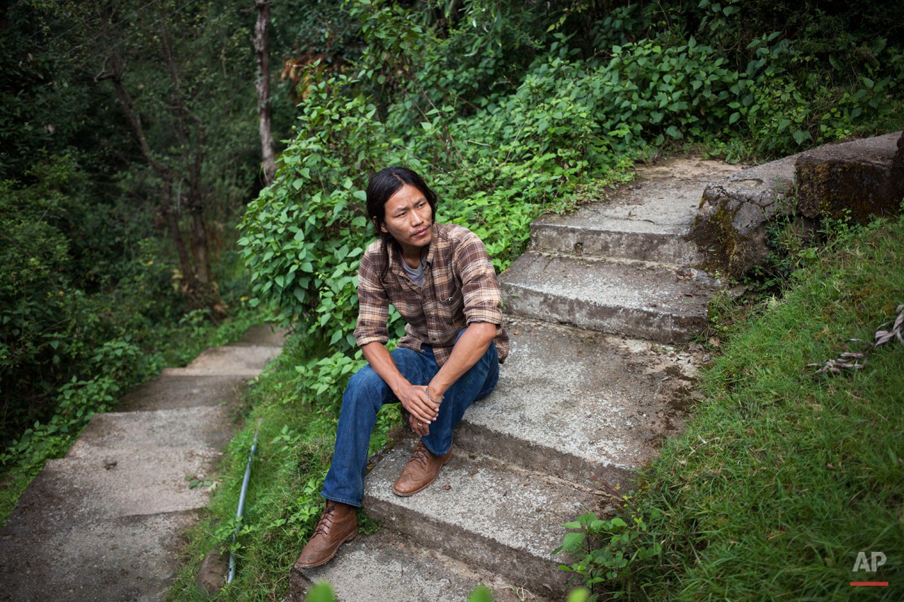  In this Thursday, Sept. 25, 2014 photo, exile Tibetan Tsering Choephel, 26, rests on concrete stairs in Dharmsala, India. Choephel left his home in Tibet 23 years ago. Sometimes, he dreams of seeing his family again. Often, he mourns the fact that h