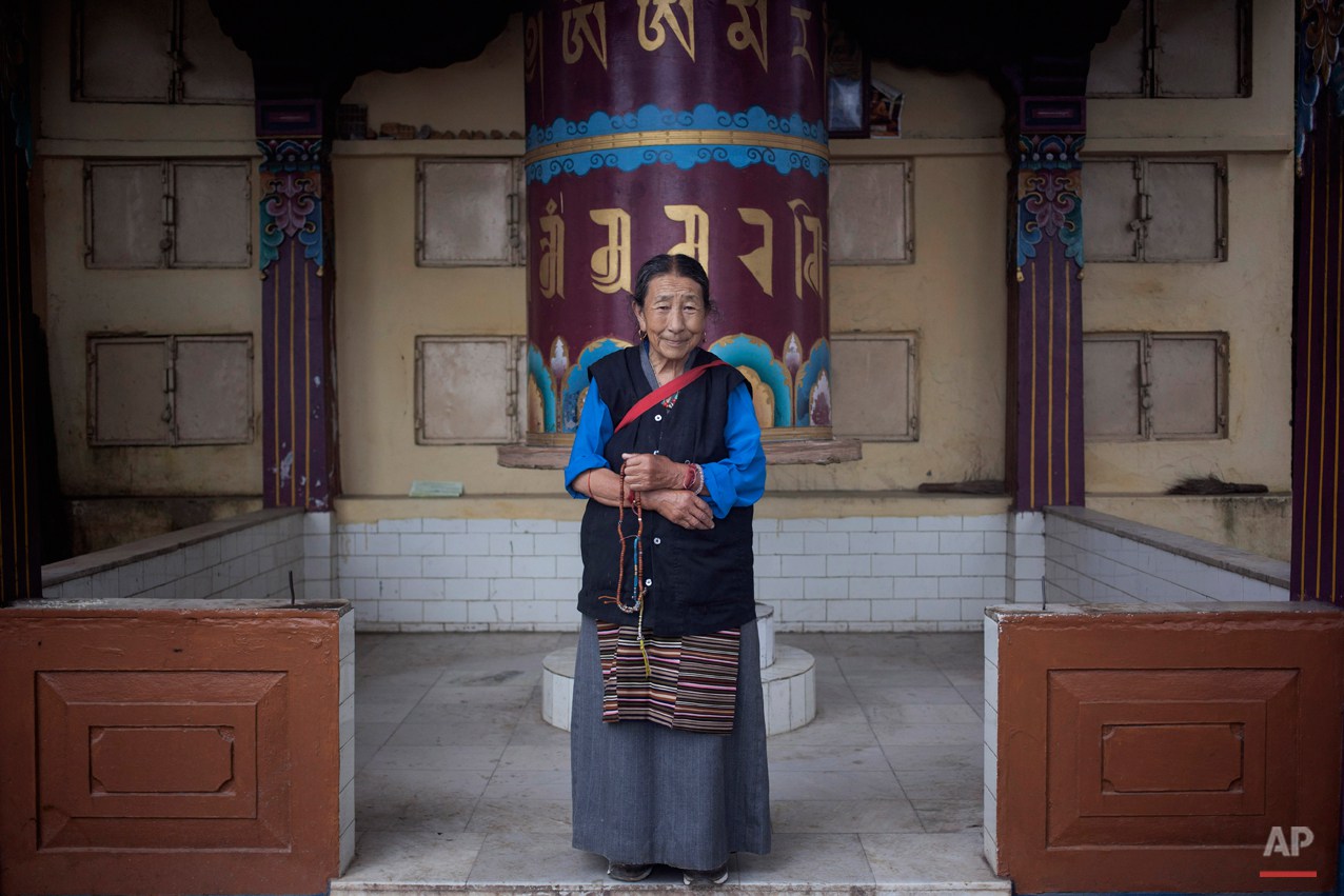  In this Thursday, Sept. 25, 2014 photo, Sonam Dolma, 75, poses for a photo near a prayer wheel in Dharamsala, India. Dolma escaped from Tibet in 1959 and made Dharmsala her home. She says she wishes to visit Tibet someday. (AP Photo/Tsering Topgyal)