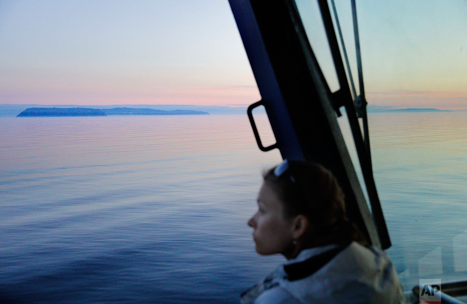  Researcher Daria Gritsenko looks out toward the American island of Little Diomede, Alaska, near left, and behind it on the right, the Russian island of Big Diomede, as the Finnish icebreaker MSV Nordica sails along the international date line throug