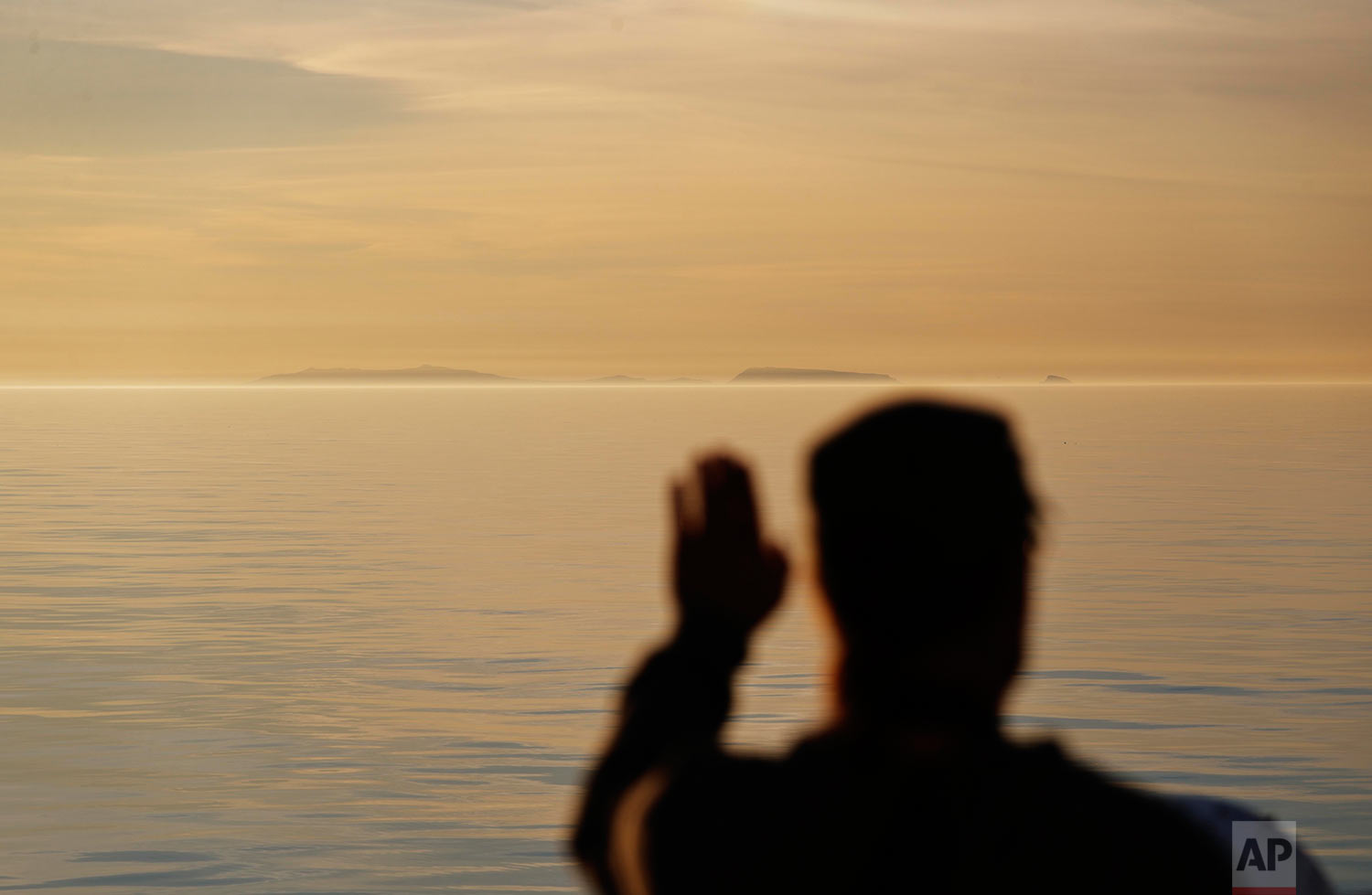  Researcher Ari Laakso shields his eyes from the midnight sun while approaching the American island of Little Diomede, Alaska, right, and the Russian island of Big Diomede, left, as the Finnish icebreaker MSV Nordica sails along the international dat