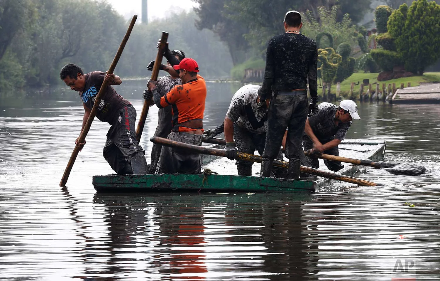In this July 13, 2017 photo, men remove mud from a shallow channel so that tourist boats will be able to move through the channel, in Xochimilco, Mexico City. (AP Photo/Marco Ugarte)