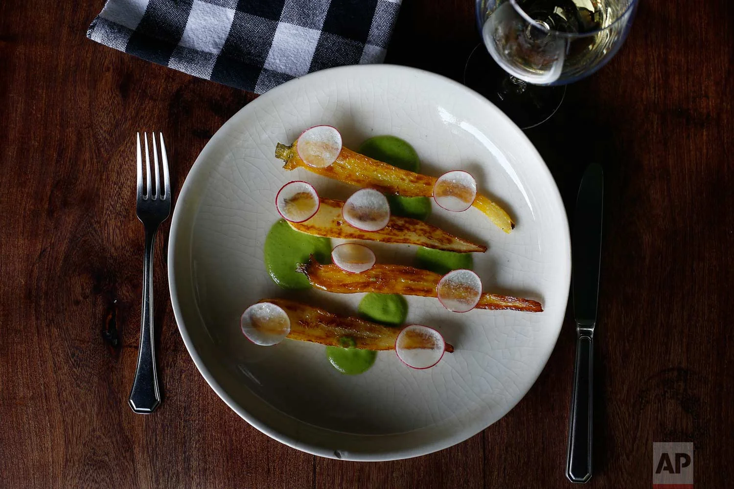 This July 14, 2017 photo shows a plate garnished with chinampa-grown roasted yellow carrots with asparagus puree, prepared by chef Eduardo Garcia, founder of Maximo Bistrot and a former U.S. migrant worker, at his restaurant in Mexico City. (AP Photo/Marco Ugarte)