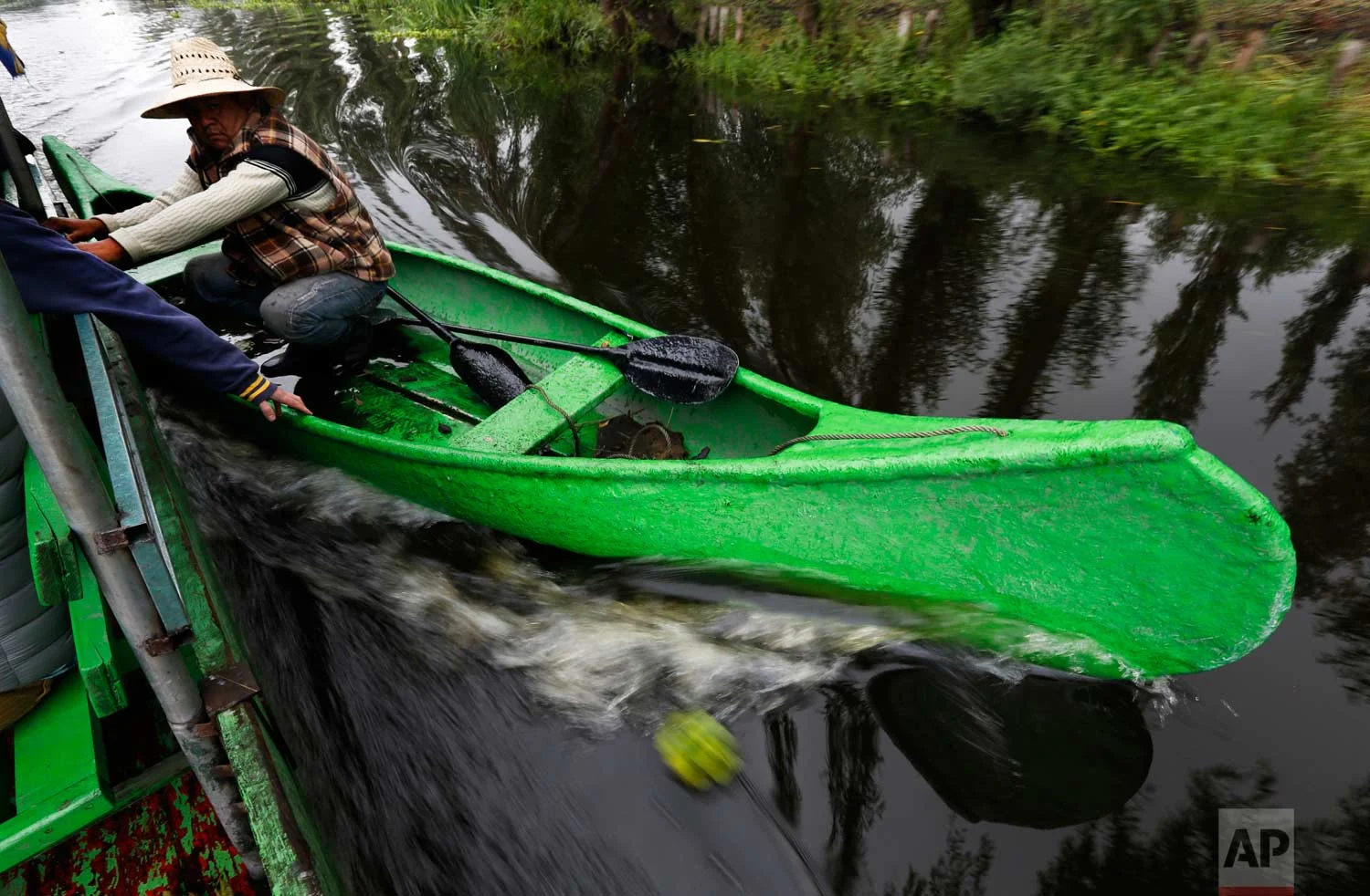 In this July 13, 2017 photo, a farmer takes advantage of a motorized boat to move faster along the channels of Xochimilco to his floating farm known as a "chinampa" in Mexico City. (AP Photo/Marco Ugarte)