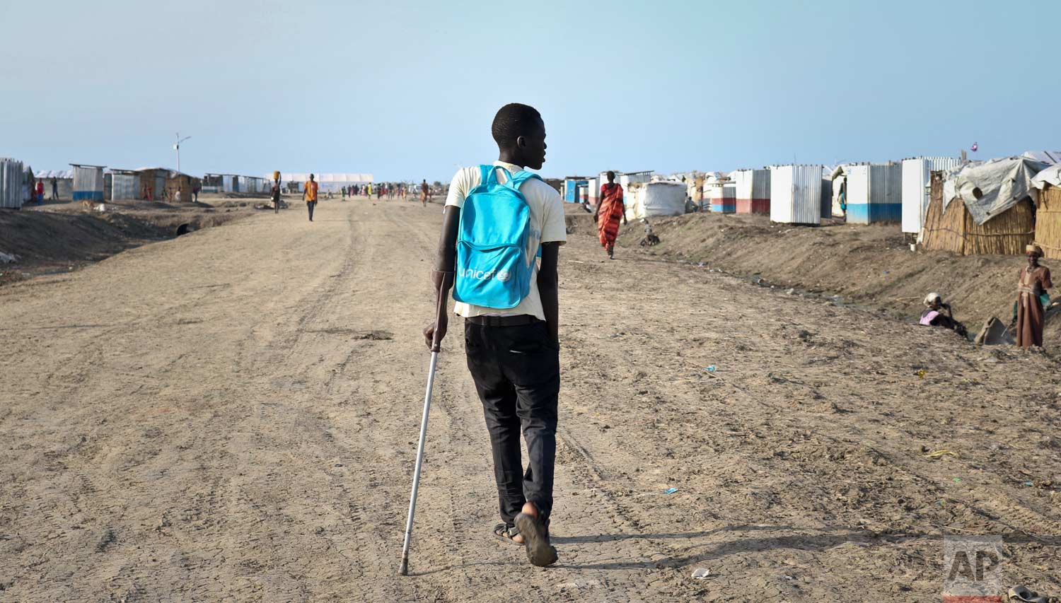 In this photo taken Monday, May 29, 2017, former child soldier James walks down the road from his small hut in a protection of civilians site to his first day at his new school, after recently being reunited with his mother who had thought he was dead, in Bentiu, South Sudan. (AP Photo/Sam Mednick)