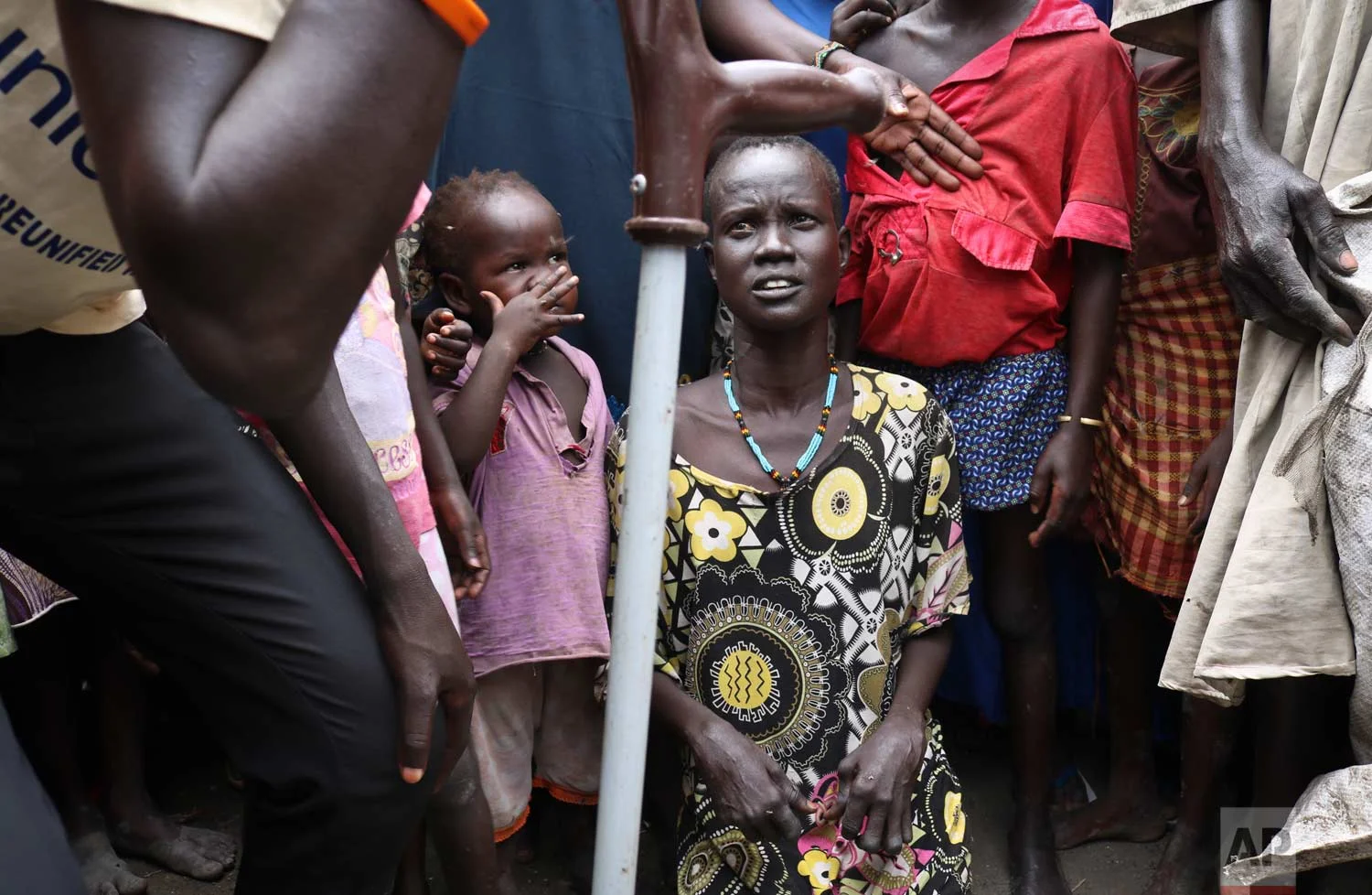 In this photo taken Friday, May 26, 2017, mother Nyayan Koang, who is unable to stand up due to polio, gazes at her son James, a former child soldier walking with a crutch, left, minutes after they were reunited and she saw him for the first time in 3 years, at a protection of civilians site in Bentiu, South Sudan. (AP Photo/Sam Mednick)