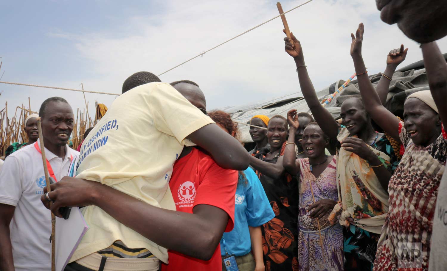 In this photo taken Friday, May 26, 2017, former child soldier James, center-left, is hugged by a community member as he is welcomed home and sees his mother for the first time in 3 years, at a protection of civilians site in Bentiu, South Sudan. (AP Photo/Sam Mednick)