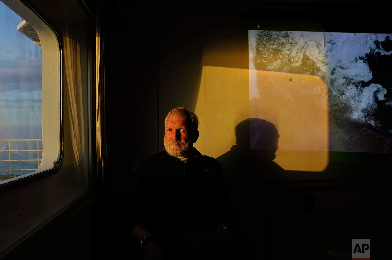 Ice navigator, Capt. David "Duke" Snider, 60, a Canadian Coast Guard veteran with 35 years at sea, sits for a portrait aboard the Finnish icebreaker MSV Nordica next to a satellite image of ice conditions along the Northwest Passage as the ship sails the Chukchi Sea into the Arctic, Saturday, July 15, 2017. Snider, who is aboard to help guide the ship safely through the ice, has sailed into the Arctic hundreds of times and completed the entire passage twice. "Maneuvering a ship in ice takes an entirely different set of skills. You have to understand how ice moves and grows," said Snider. "It's a dance, a slow dance. That's what it's all about, getting the ship through without stepping on her toes." (AP Photo/David Goldman)