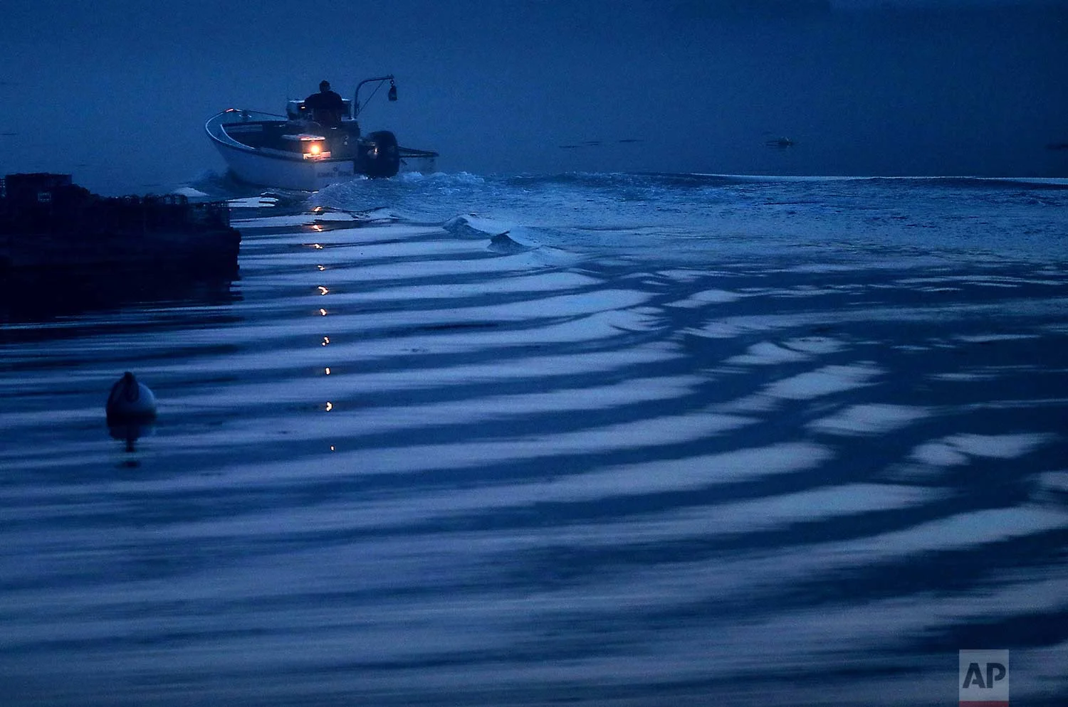 A lobsterman's boat leaves a gentle wake as he motors out of a harbor on a foggy morning, Friday, July 21, 2017, in Boothbay, Maine. (AP Photo/Robert F. Bukaty)