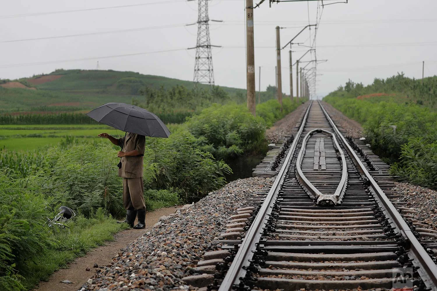 In this Friday, July 21, 2017, photo, a man stands near the pathway leading to where an unexploded bomb was found near the railway which runs through Hamhung from Pyongyang to the northeastern port of Chongjin. (AP Photo/Wong Maye-E)