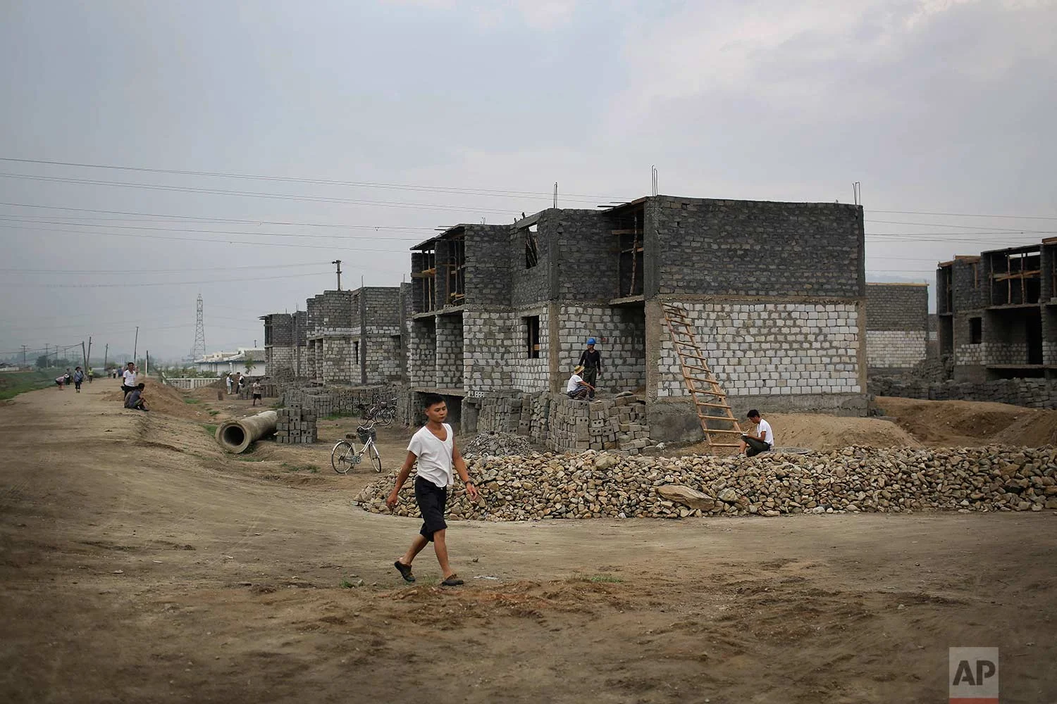 In this Friday, July 21, 2017, photo, a man walks past a construction site on the outskirts of Hamhung, North Korea's second-largest city, where construction workers unearthed a rusted but still potentially deadly mortar round in February. North Korea is just one of many countries still dealing with the explosive legacy of major wars. But the three-year Korean War, which ended in what was supposed to be a temporary armistice on July 27, 1953, was one of the most brutal ever fought. (AP Photo/Wong Maye-E)