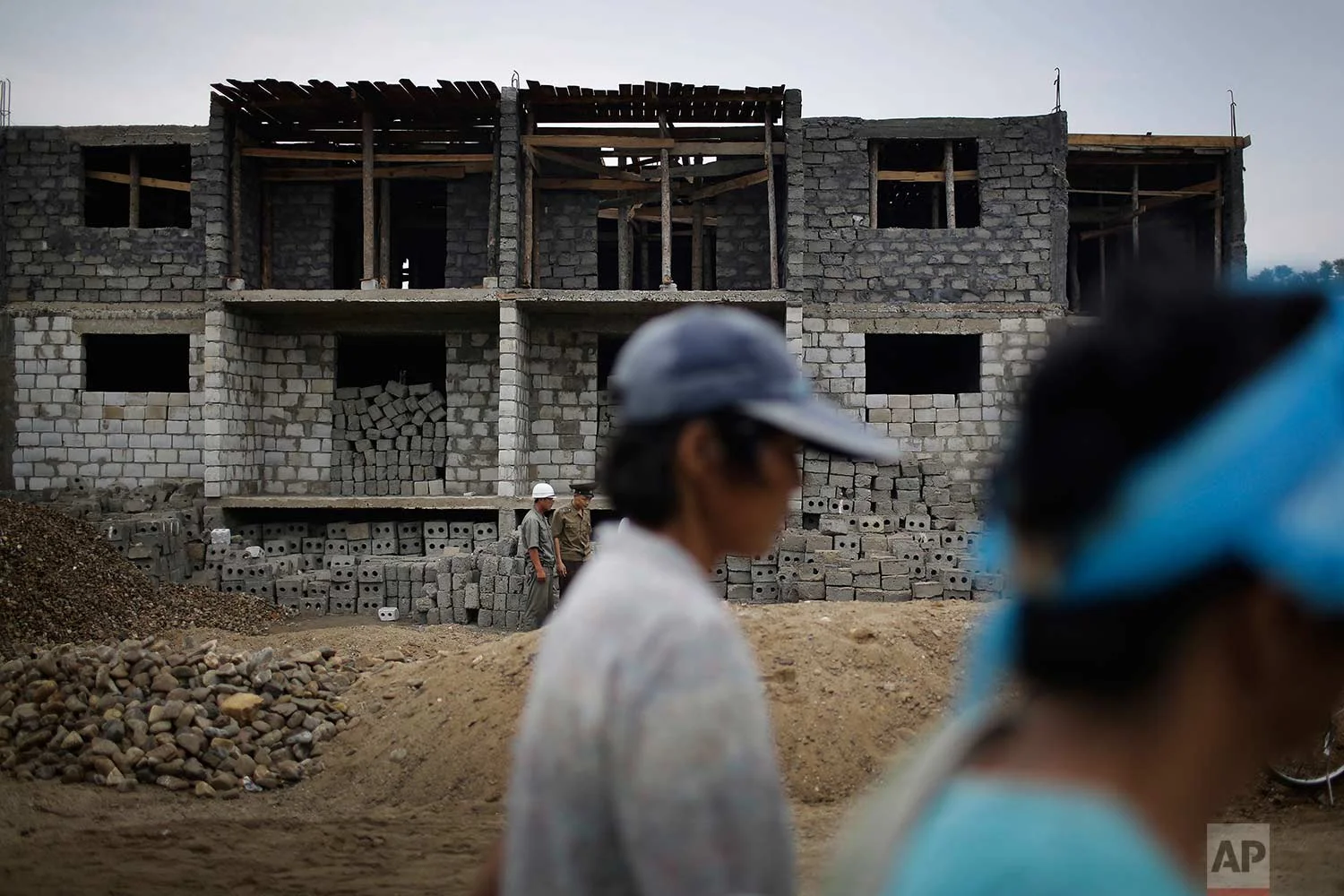 In this Friday, July 21, 2017, photo, women walk past a construction site on the outskirts of Hamhung, North Korea's second-largest city, where construction workers unearthed a rusted but still potentially deadly mortar round in February. (AP Photo/Wong Maye-E)